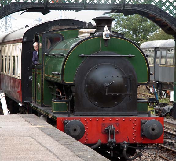 0-6-0ST on a passenger train comes under the foot bridge and into the station at  Castle Hedingham